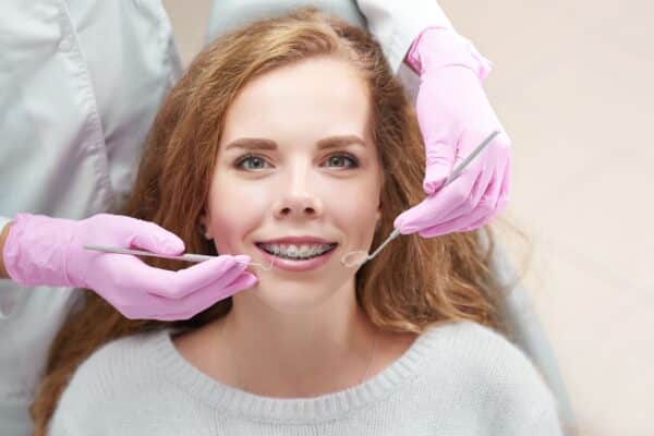 A teenage female patient with clear ceramic braces smiling during a dental checkup