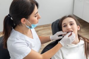 : A dental professional in a clinic using a handheld 3D intraoral scanner to map a patient's teeth